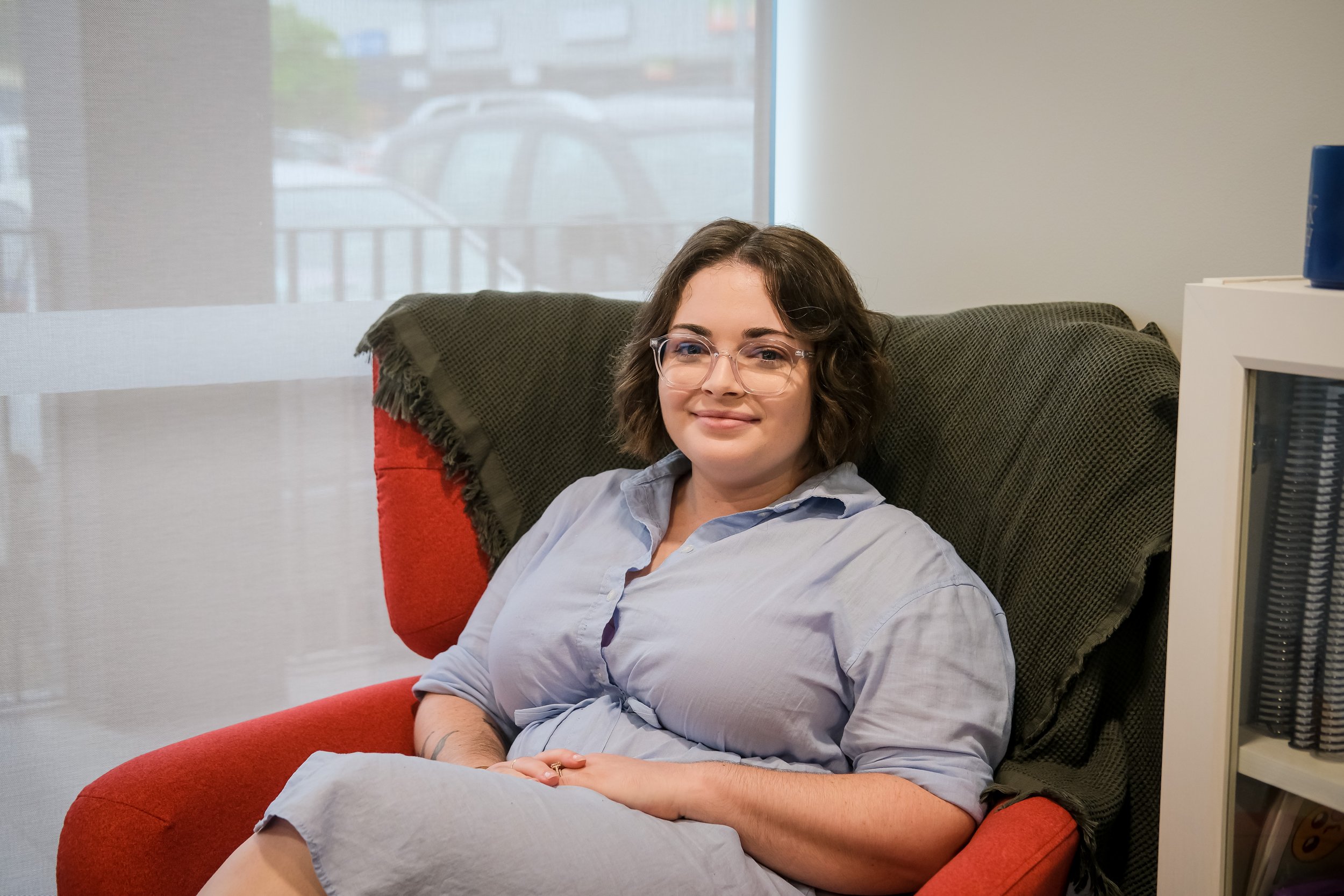 Bri - Administration & Finance Officer sitting in a red chair smiling at the camera